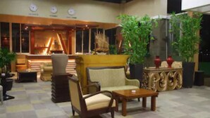 A lobby with a checkered floor, a reception desk, seating area with chairs and a sofa, and decorative plants. - Marbella Suites Bandung (Bandung)