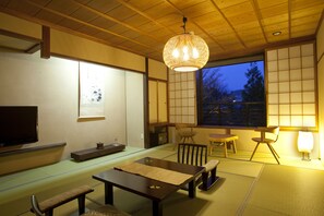 A traditional Japanese room with tatami flooring, a low table, a bench, and a television. - Hidatei Hanaougi (Takayama)
