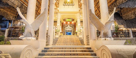 Una escalera de diseño singular que conduce a un espacio central con una araña y columnas.