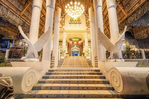 A staircase with a unique design, leading to a central area with a chandelier and columns.
