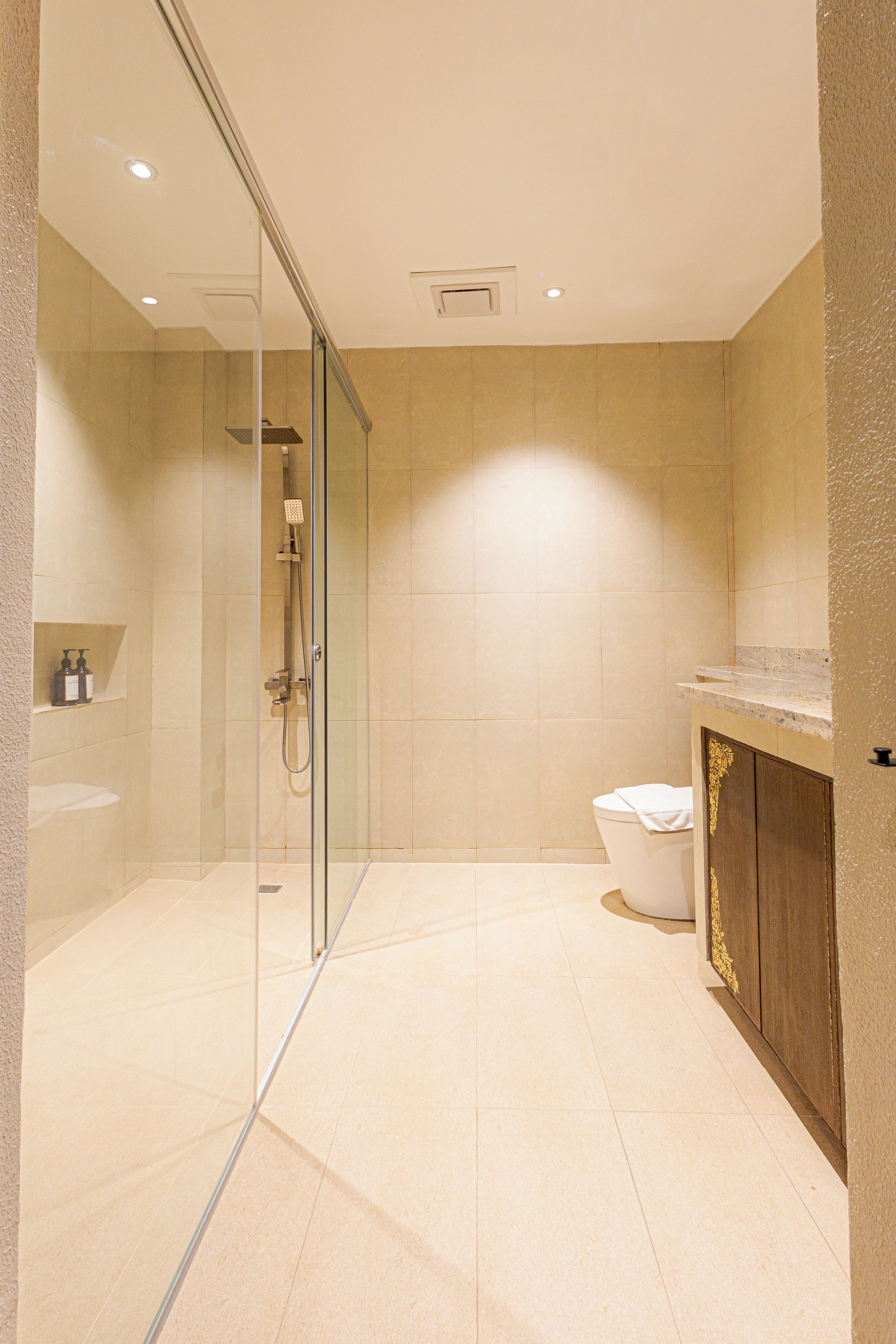Un baño moderno con ducha envuelta en vidrio, inodoro y tocador con encimera de mármol.