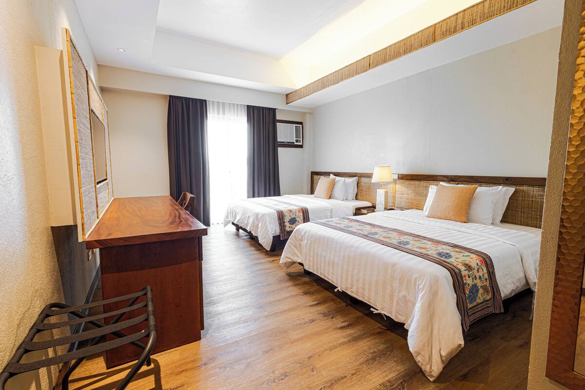 A hotel room with two beds, a desk, and a chair.