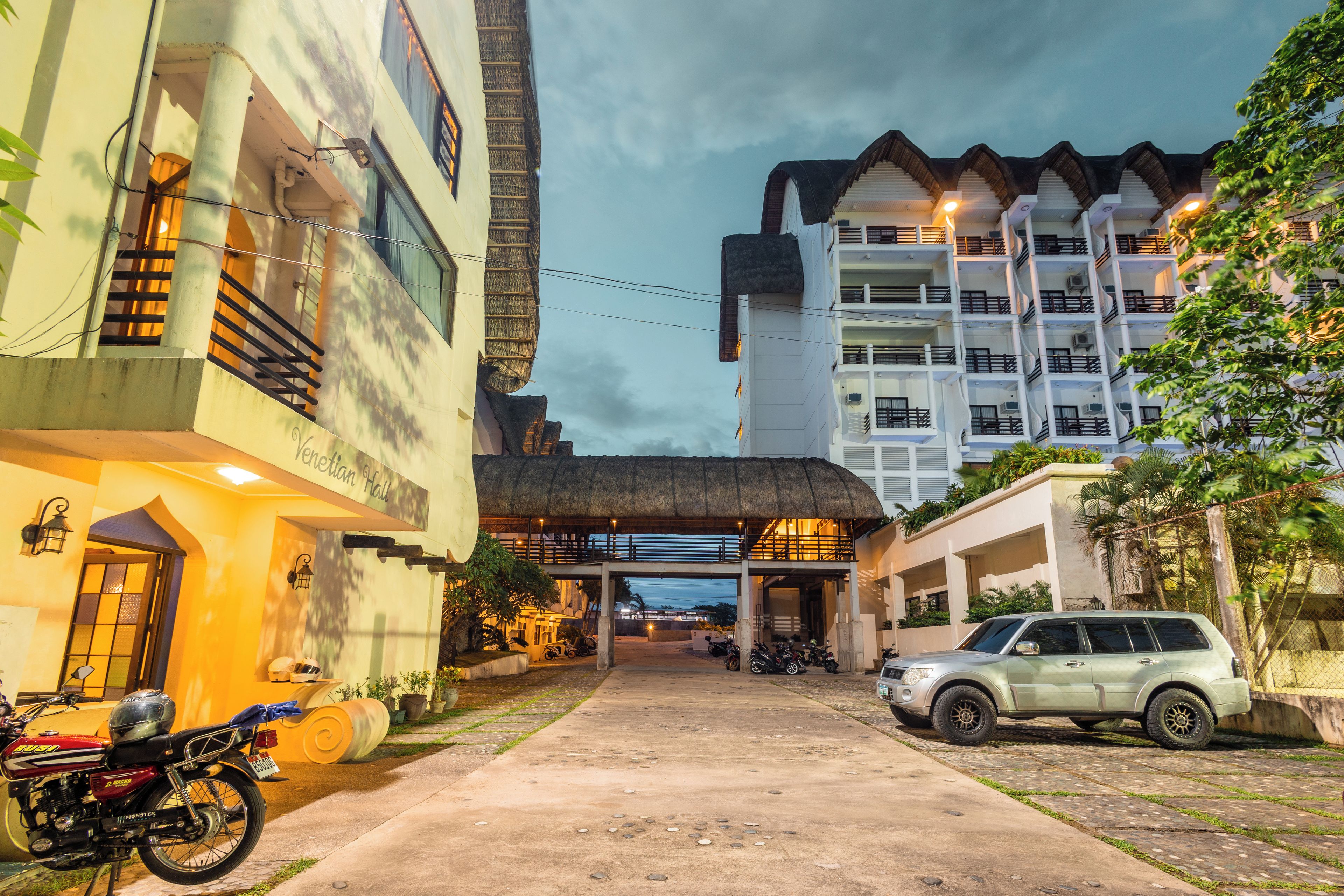 A hotel entrance with a covered walkway, a parked motorcycle, and a car.