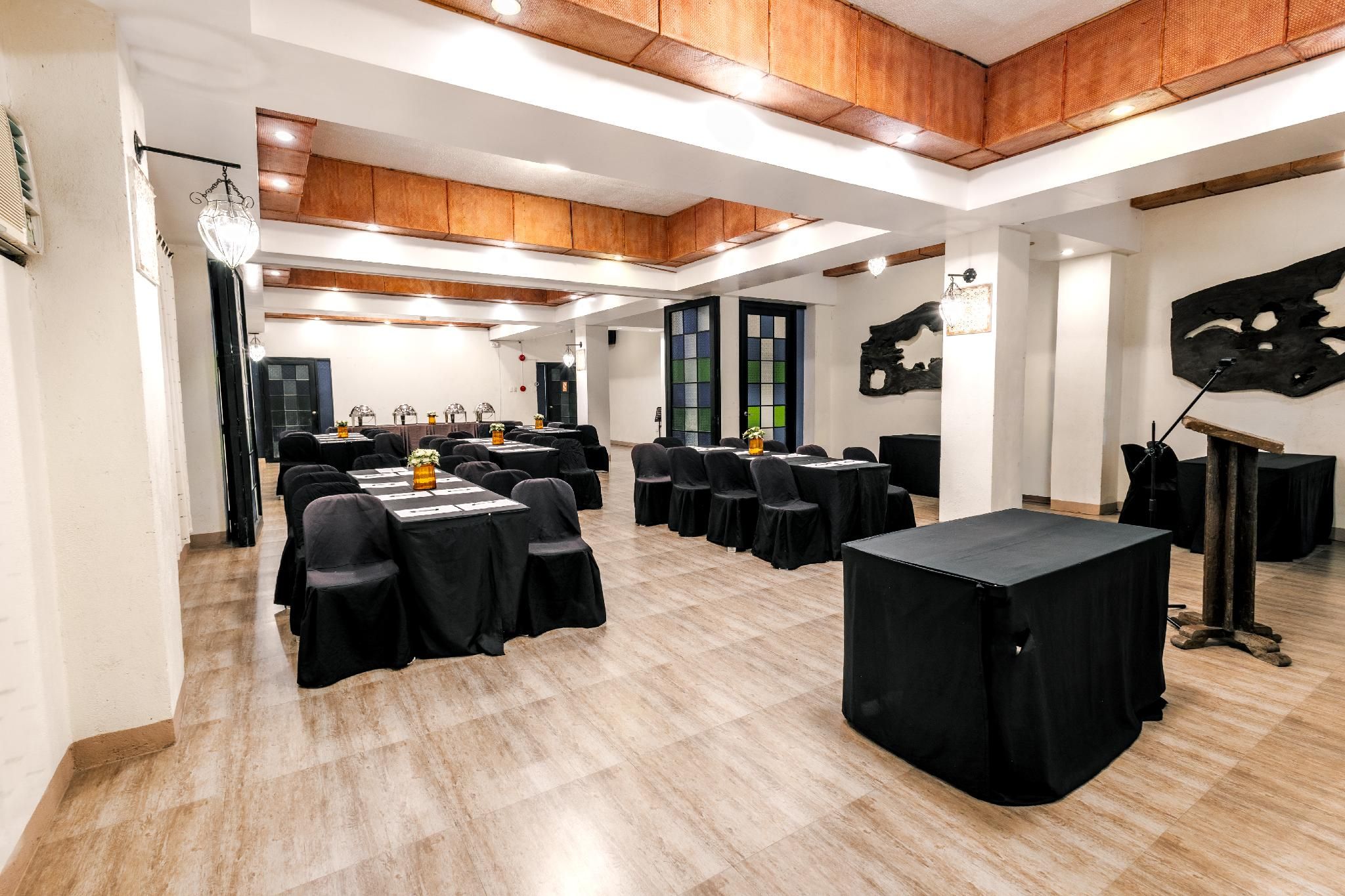 A conference room with tables and chairs, wooden flooring, and a modern ceiling design.