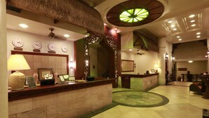 A hotel reception area with a reception desk, clocks, and a decorative ceiling.