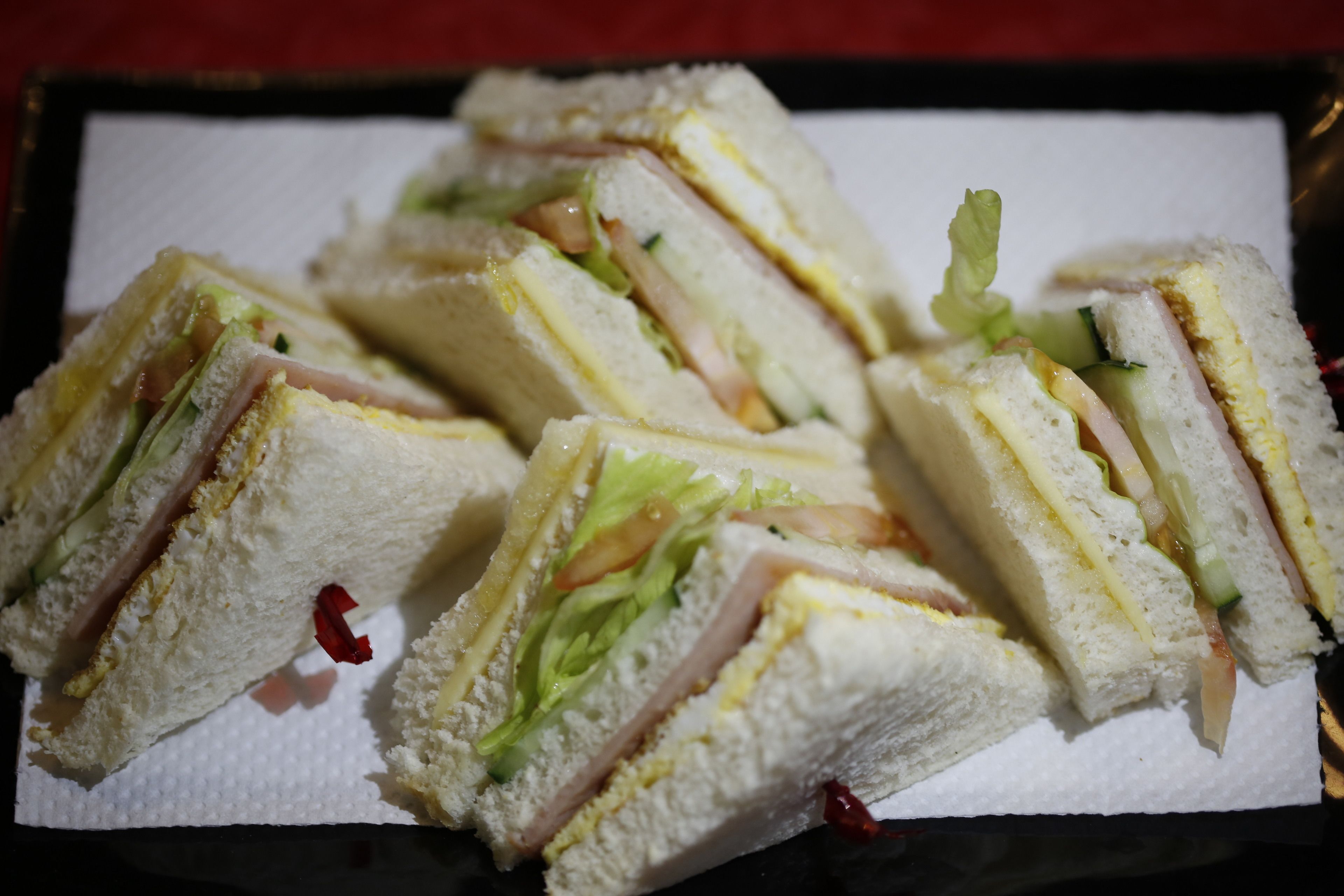 A tray of sandwiches cut into triangles, placed on a paper liner.
