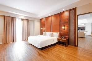 Une chambre d’hôtel avec un grand lit, des boiseries, une table de chevet avec un téléphone et une vue sur le couloir.