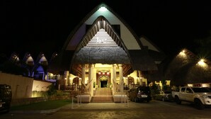 A hotel entrance with a thatched roof, steps leading up to the door, and a sign above the entrance.