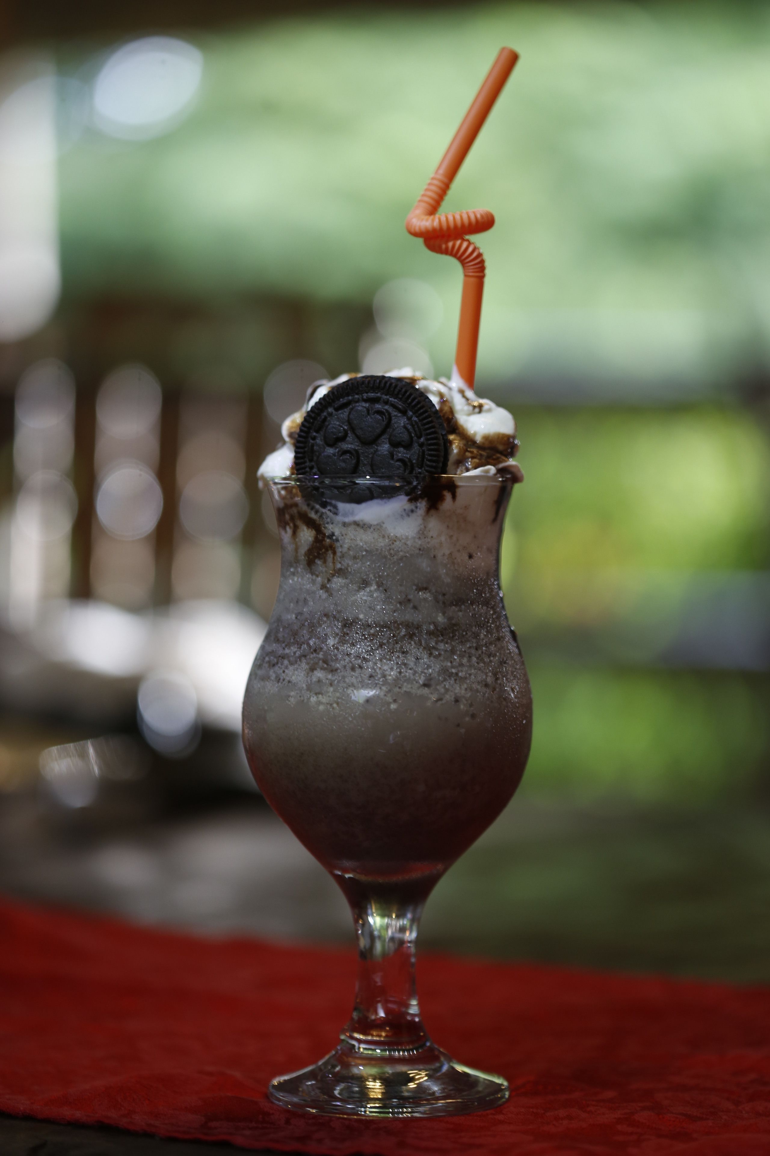 Un verre avec une paille, une boule de glace et un biscuit Oreo sur le dessus.