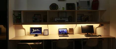Un escritorio con dos monitores, una computadora portátil y un teclado. Hay dos sillas frente al escritorio.