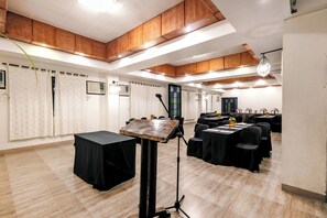 Een vergaderruimte met tafels, stoelen, een spreekgestoelte en een kroonluchter.