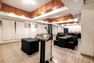 Un salón de conferencias con mesas, sillas, un atril y una araña.