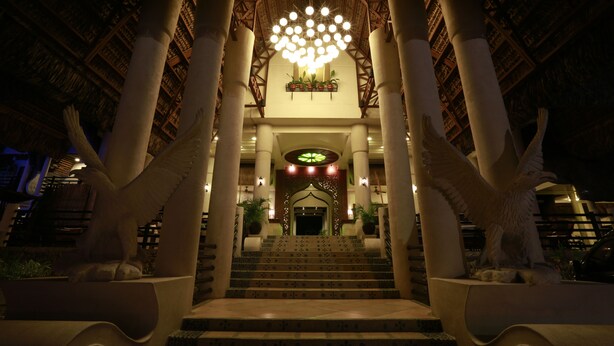 A grand staircase leading to a building entrance, flanked by large columns and statues.