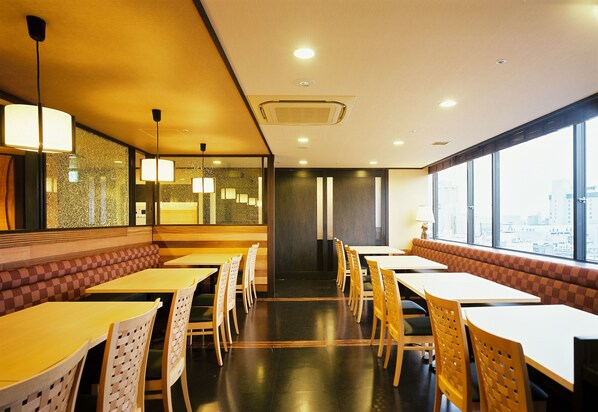 A restaurant with high tables and booths, large windows, and a city view.