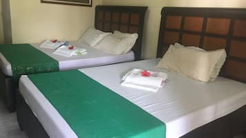 Habitación de hotel con dos camas, cada una con cubrecama verde y ropa blanca. Hay un cuadro en la pared sobre las camas.