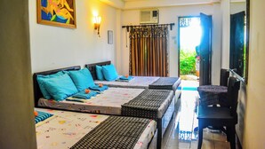 A hotel room with three beds, a dining table, and a chair. There is a painting on the wall and an air conditioning unit above the door. - Rio Grande de Laoag Resort Hotel (Laoag)