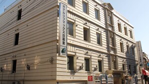 A multi-story building with a beige facade, multiple windows, and a sign indicating it is a hotel. - Hotel Livemax Nippori, Tokyo (Tokyo)