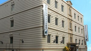 A multi-story hotel with a classic architectural design, featuring a prominent entrance with a balcony and a sign indicating it is a hotel. - Hotel Livemax Nippori, Tokyo (Tokyo)
