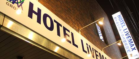 Une enseigne d’hôtel portant le nom « HOTEL LIVENMAX » et une plus petite enseigne au-dessus indiquant également « HOTEL LIVENMAX ».