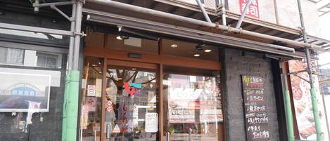 Un restaurant de sushis avec une grande enseigne, une entrée en verre et un panneau affichant le menu à l’extérieur.