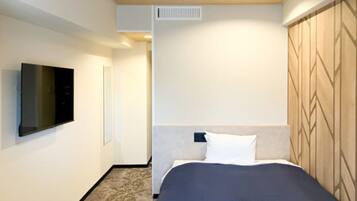 Habitación de hotel con cama, televisor de pantalla plana montado en la pared y cabecero estampado.