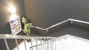 Una escala amb barana metàl·lica, una planta en test i un senyal indicador penjat a la paret.