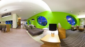 A modern hotel lobby with a curved ceiling, green walls, and large windows offering city views. - Hampton Inn by Hilton Ciudad del Carmen Campeche (Ciudad del Carmen)