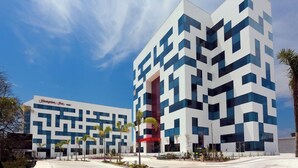 A modern hotel with a geometric facade, featuring a prominent red vertical element and a clear sky. - Hampton Inn by Hilton Ciudad del Carmen Campeche (Ciudad del Carmen)