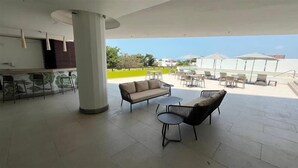 An outdoor patio area with a sofa, chairs, and a small table. There is a pool in the background. - Hampton Inn by Hilton Ciudad del Carmen Campeche (Ciudad del Carmen)