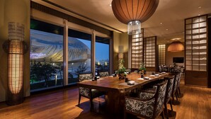 A spacious dining area with a large wooden table, patterned chairs, and a view of a modern building outside. - Hilton Dalian (Dalian)