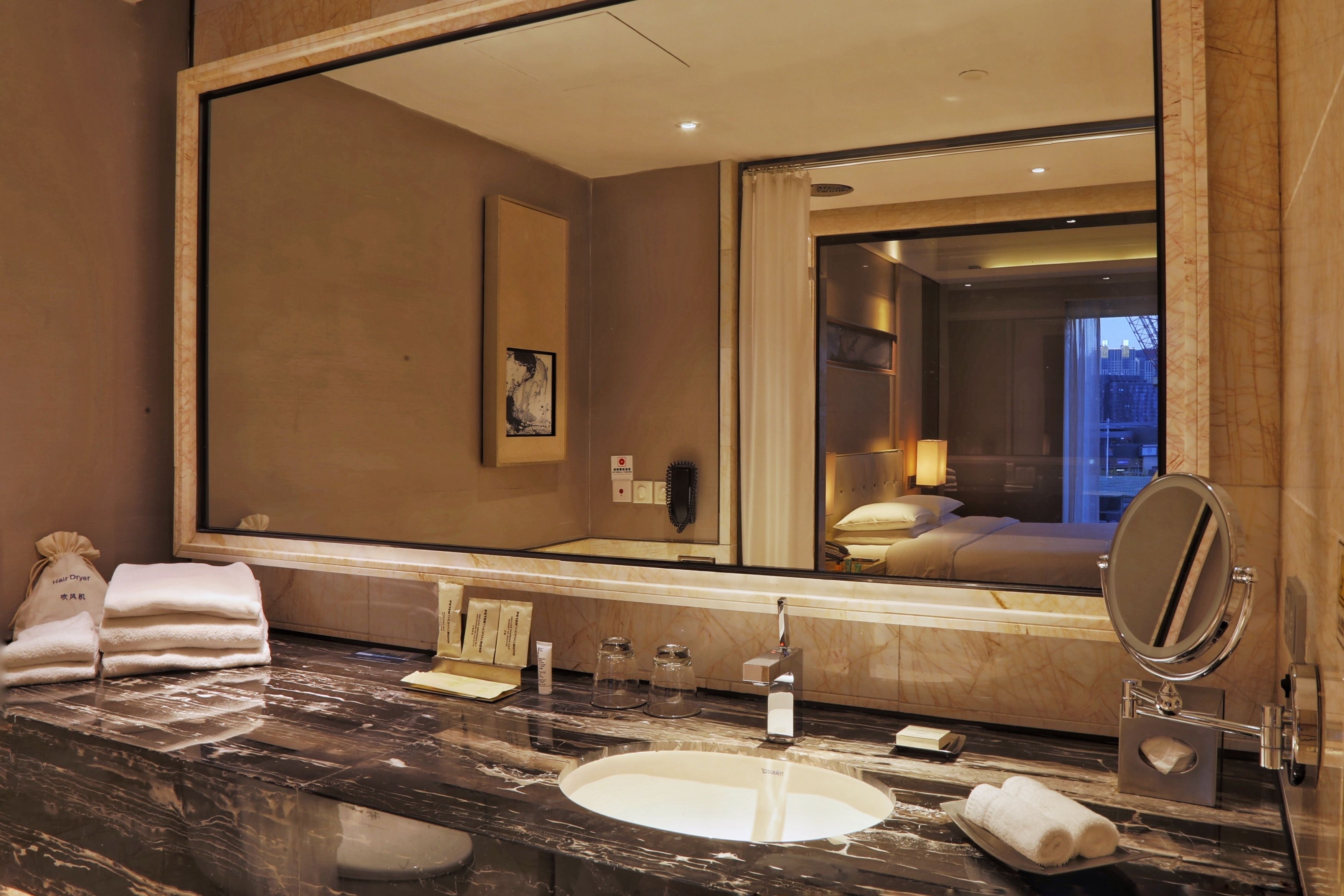 Un baño de hotel con un espejo grande, un lavamanos de mármol y toallas.