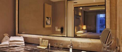 Un baño de hotel con un espejo grande, un lavamanos de mármol y toallas.