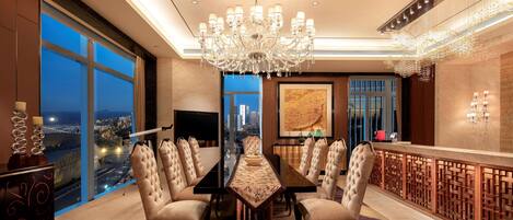 A luxurious dining room with a large chandelier, a city view, and a modern bar area.
