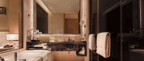 A modern bathroom with a large mirror, dual sinks, a glass shower enclosure, and a towel rack.