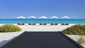 A beachside walkway leading to lounge chairs with umbrellas. - Park Hyatt Abu Dhabi Hotel & Villas (Abu Dhabi)