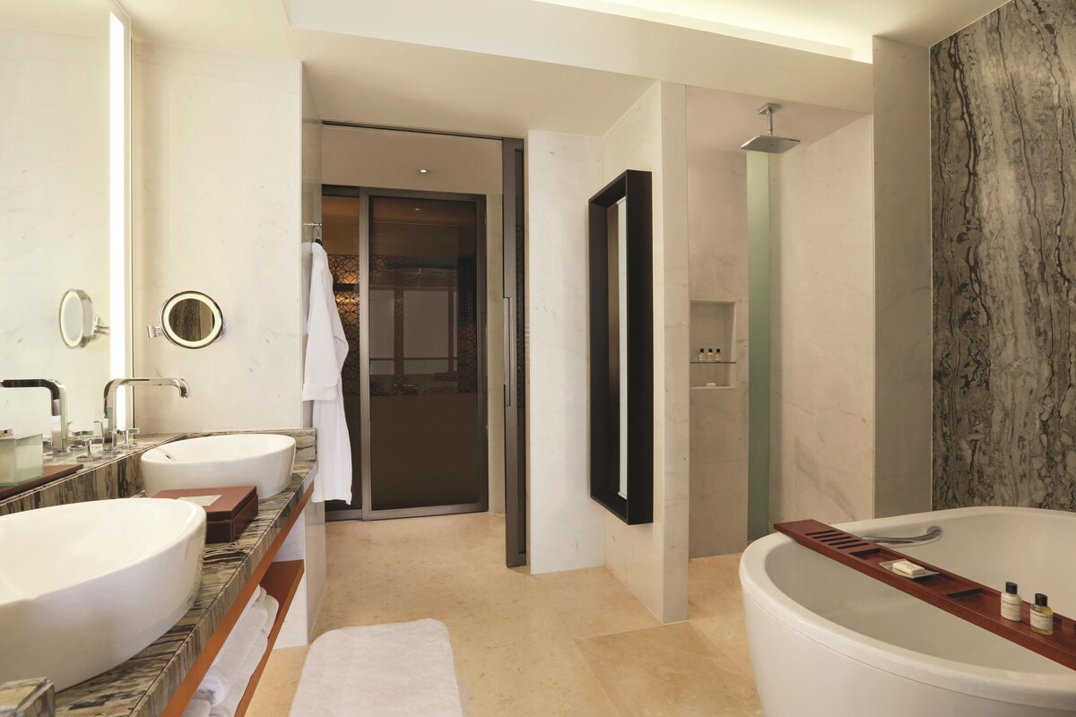 A modern bathroom with two sinks, a large bathtub, and a shower.