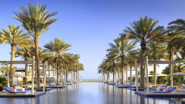 A pool area with lounge chairs, palm trees, and a view of the sea. - Park Hyatt Abu Dhabi Hotel & Villas (Abu Dhabi)