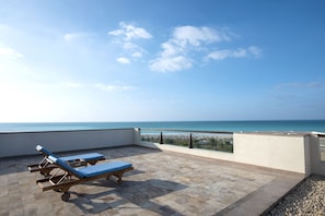 Relax in a tranquil outdoor space with comfortable lounge chairs and a stunning beach view.