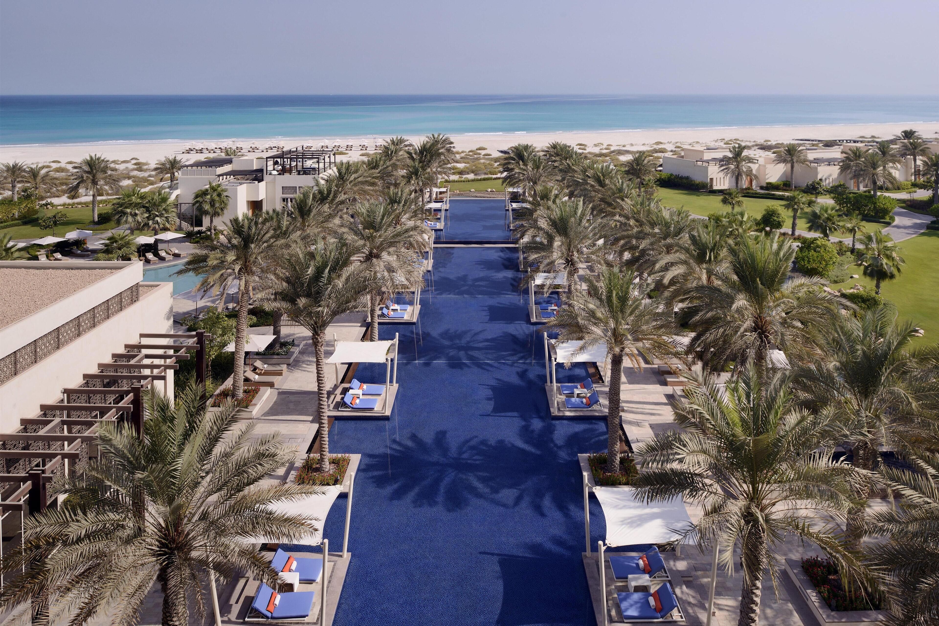 Un resort con piscina, palmeras y vista al mar.
