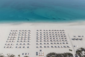 An aerial view of a beach with rows of white tents and umbrellas arranged in a grid pattern, with a clear view of the ocean in the background. - Park Hyatt Abu Dhabi Hotel & Villas (Abu Dhabi)