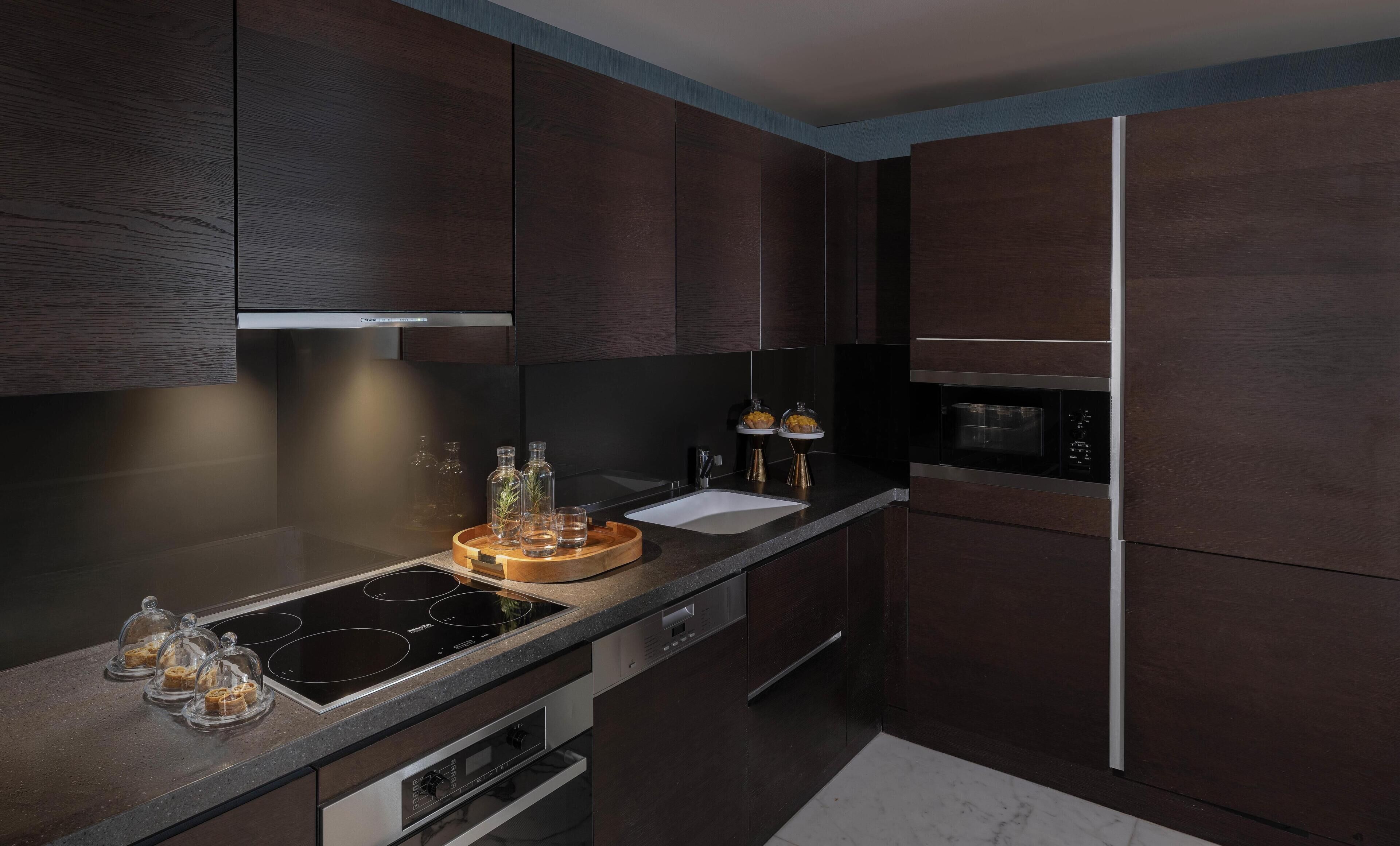 A modern kitchen with dark wood cabinets, a stainless steel range, and a built-in microwave.