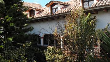 A building with a tiled roof, arched windows, and a garden with various plants.