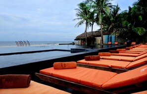 Una piscina al aire libre, sombrillas, sillones reclinables de piscina