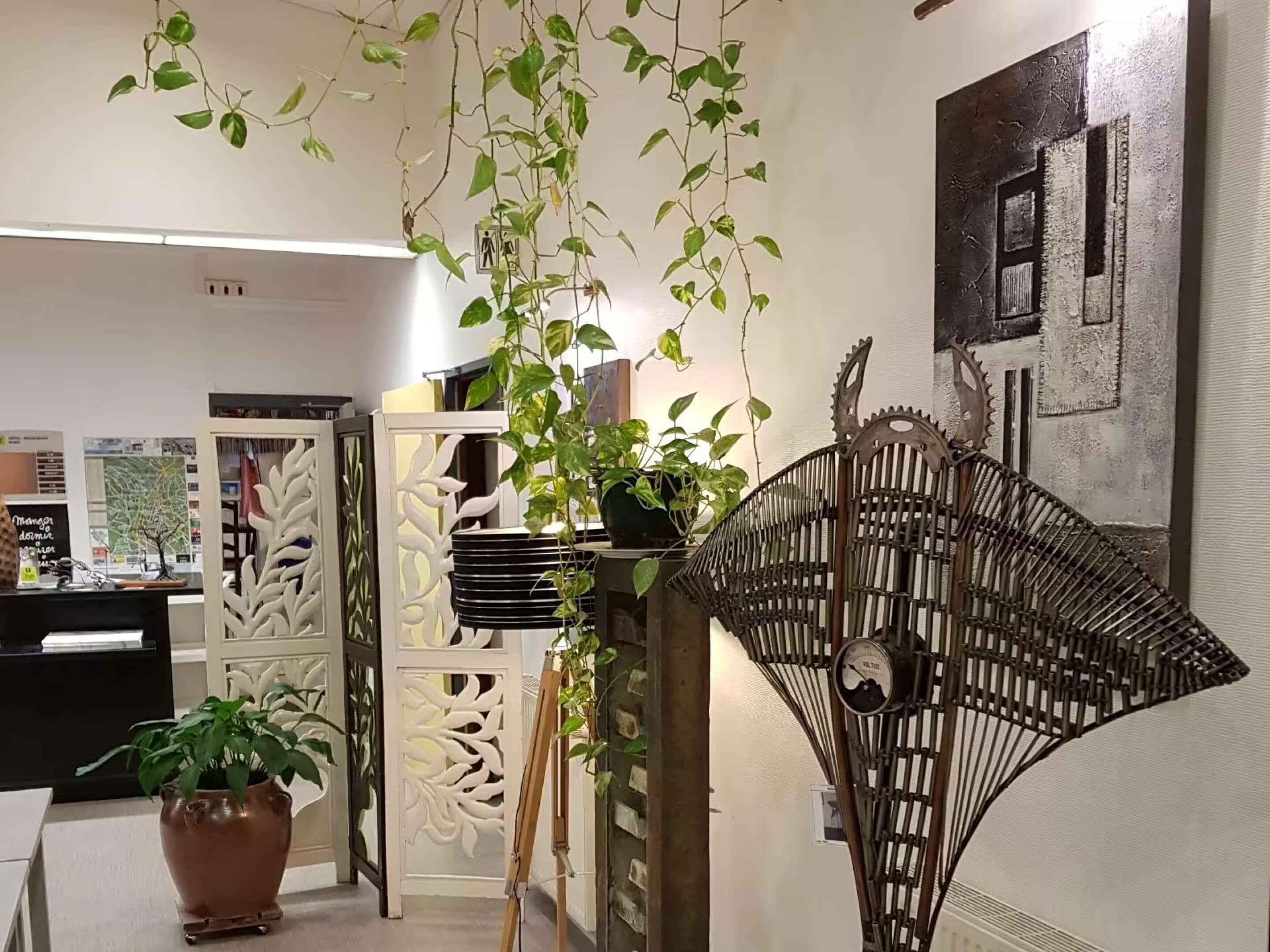 A room with a white decorative partition, a potted plant, and a wall-mounted clock.