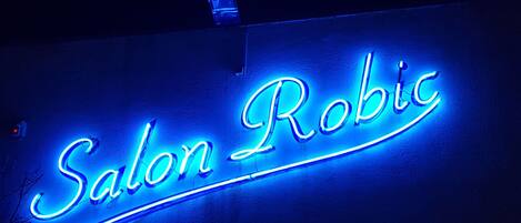 A neon sign for 'Salon Robic' on a building facade.