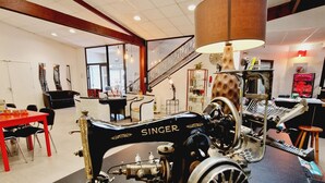 A vintage Singer sewing machine on display in a room with a staircase, a dining area, and a large window.
