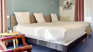 A hotel room with a large bed, a bedside table, a chair, and a window with curtains.