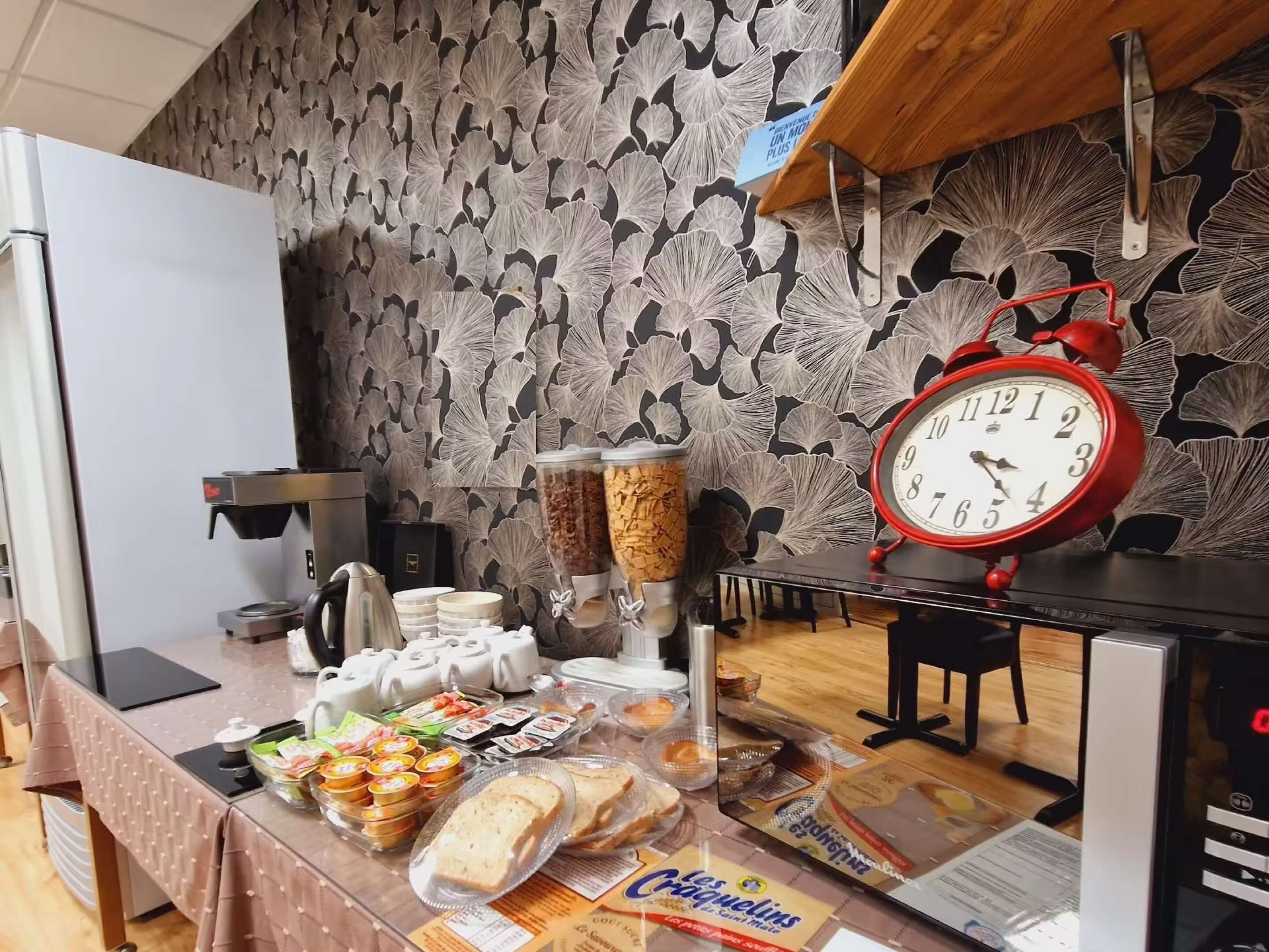 A breakfast buffet setup with a clock, coffee machine, and various food items.