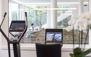 Zona de equipamiento para ejercicios, con una cinta de correr y una bicicleta estática, ambas mostrando pantallas con datos de entrenamiento.