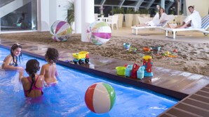 An indoor swimming pool area with children playing, a beach ball, and beach toys. - Atlantic Hotel & SPA (Riccione)